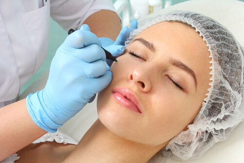 Doctor marking the face of beautiful woman for surgery