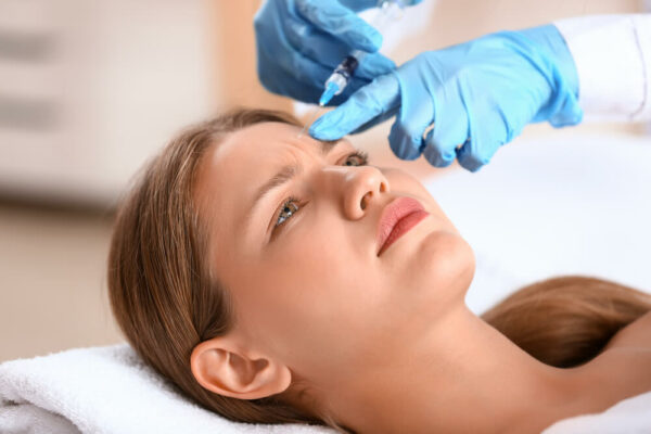 Young woman receiving injection in beauty salon